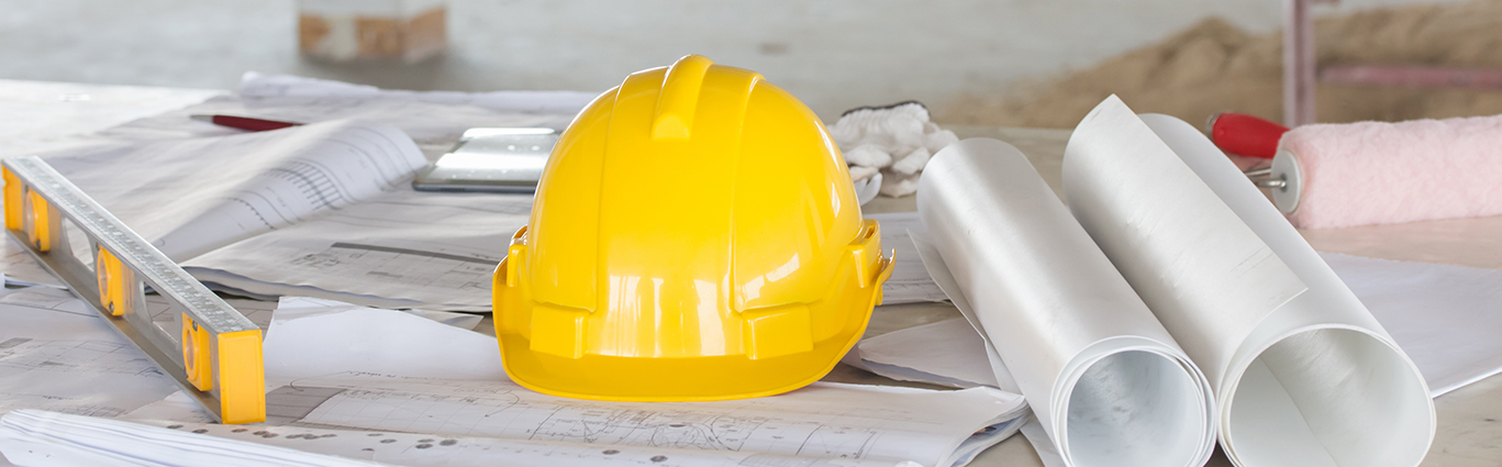 Hard hat on table with plans and level