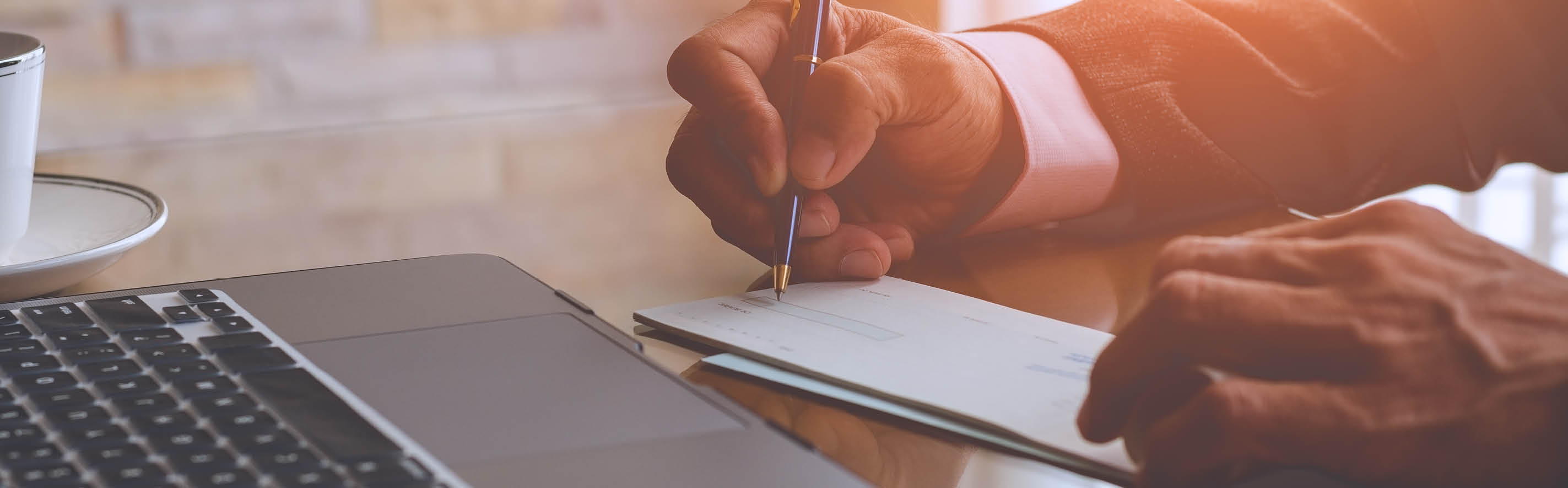 Man writing check in front of computer.