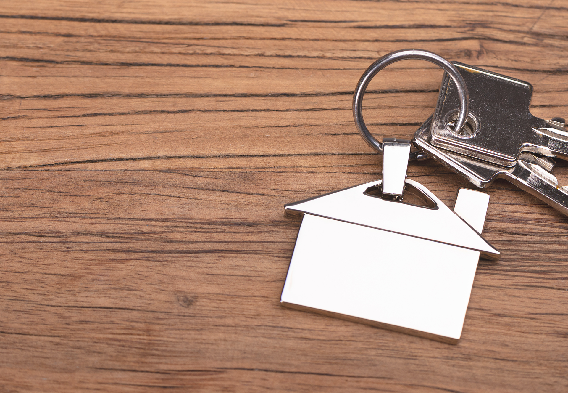 House keychain and keys sitting on wooden table.

