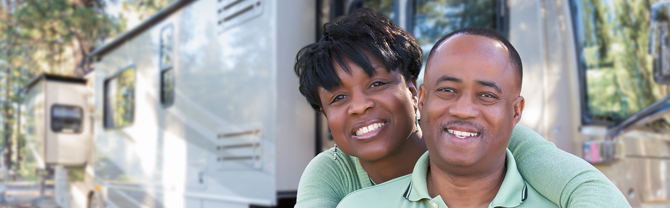 Happy African American couple in front of their RV at campground